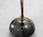 Gietijzeren theepot met bloemen en vogel