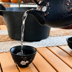 Gietijzeren theepot met vier kopjes en zeef