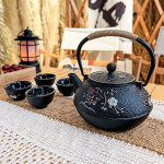 Gietijzeren theepot met vier kopjes en zeef