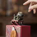 Tea pet kikker in een schommelstoel