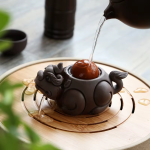 Tea pet van aardewerk met reliëfsculpturen