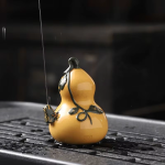 Tea pet van paarse klei met waterstraal — Geeloranje kalebas