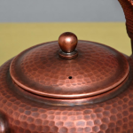 Vintage koperen theepot met hamerslag en gevlochten hengsel
