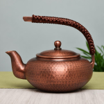 Vintage koperen theepot met hamerslag en gevlochten hengsel
