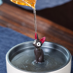 Zittende zwarte kat als tea pet voor de theetafel